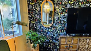 A living room with a green armchair, a woven basket, a wooden cabinet, and a large mirror on the wall. - Hillside Home: Amazing Views w/ Big Deck 5 Min. From Downtown + Trailheads! (Flagstaff)