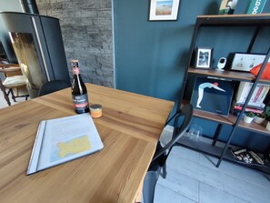 A wooden table with a bottle of Loïc Raison Brut, a small jar of chocolate spread, and a map. - Charming seaside vacation home (Pénestin)