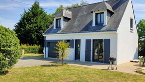 A modern two-story house with a sloped roof, a small attached garage, and a patio area with outdoor furniture. - Charming seaside vacation home (Pénestin)
