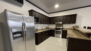 Una cocina moderna con gabinetes oscuros, electrodomésticos de acero inoxidable y una encimera de granito.