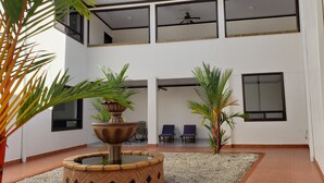 Un espacio interior moderno con una fuente central, una zona de estar y ventanas amplias.