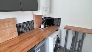 Eine kompakte Küche mit Waschmaschine, integriertem Geschirrspüler und kleiner Arbeitsplatte.
