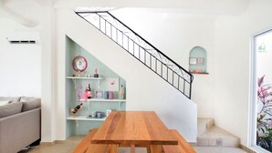 A wooden dining table with benches in a living room with a staircase and a sofa.