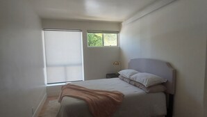 A bedroom with a bed, a window, a nightstand, and a lamp. - Attached Unit, a few minute walk from the Beach (Santa Barbara)
