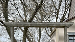 Una terraza de madera con barandillas, una casa al fondo y un letrero que indica 'No Parking'.