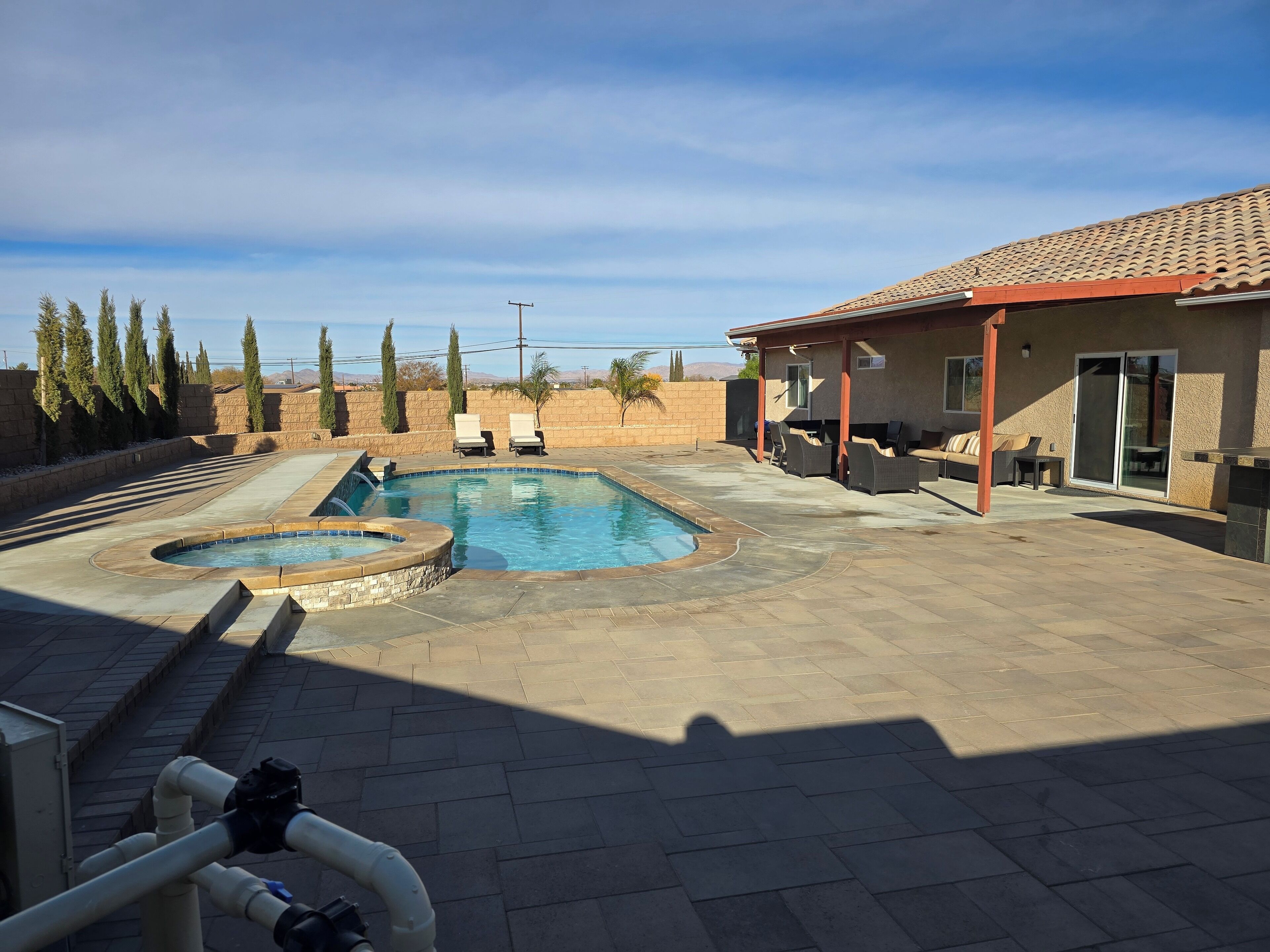 Un jardin avec une piscine, des chaises longues et un espace patio.