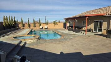 Un jardin avec une piscine, des chaises longues et un espace patio.