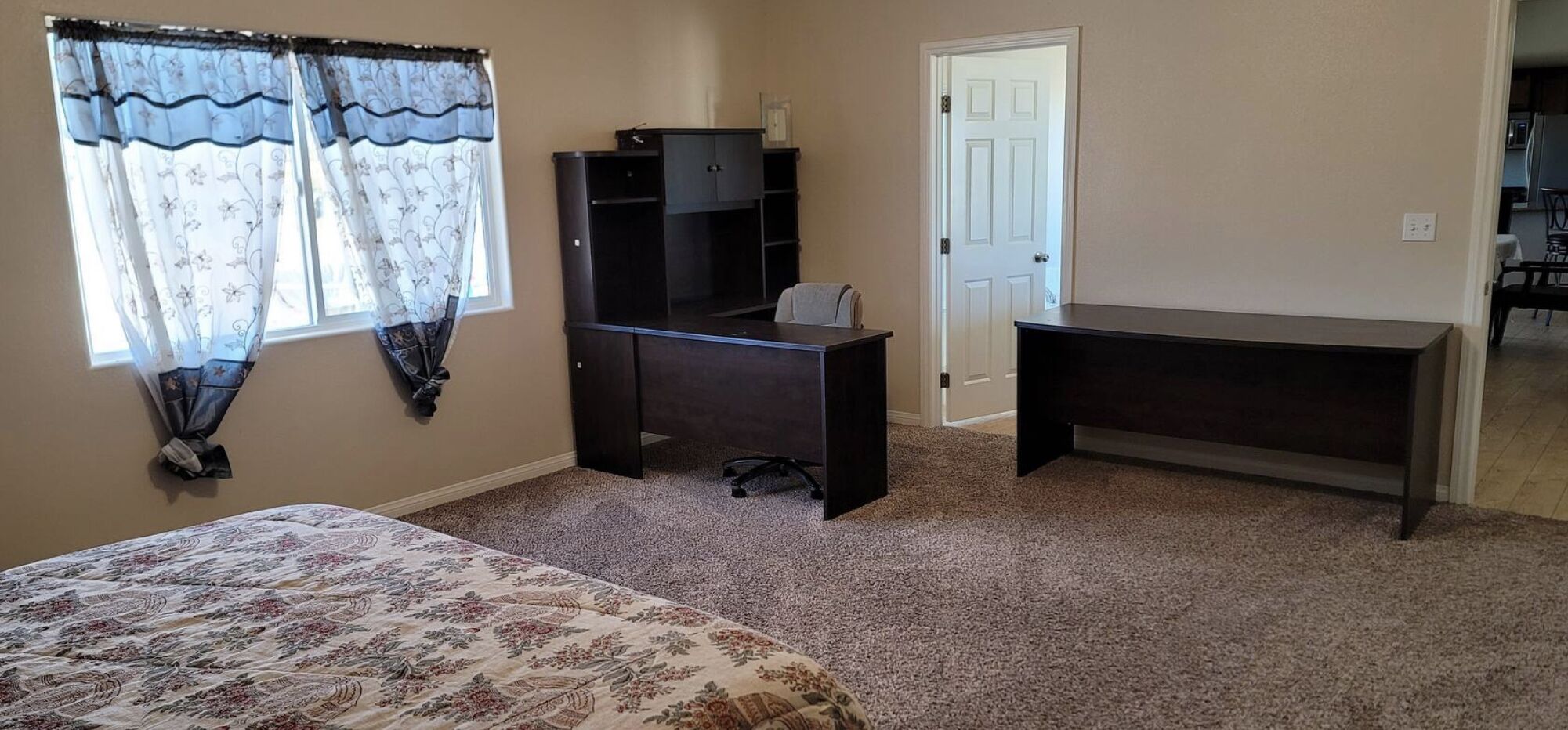 Une chambre à coucher comprenant un lit, un bureau, une chaise et une armoire.