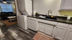 Een moderne keuken met witte kasten, een zwart aanrecht en een backsplash met een herringbone-patroon.