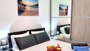 A neatly made bed with pillows, a tray of fruit and juice, and towels.