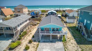 Een strandhuis met meerdere woningen, waaronder een opvallend blauw huis met balkon en zwembad.
