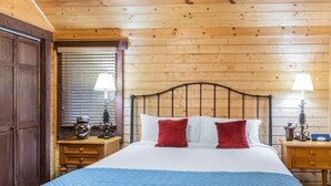 A wooden-paneled bedroom with a bed, two bedside tables, and a nightstand.