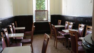 A restaurant interior with wooden tables and chairs, a black and white color scheme, and a view of greenery through a window.