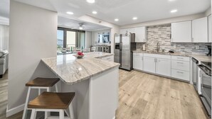 Una cocina moderna con encimera de mármol, electrodomésticos de acero inoxidable y vistas al balcón.