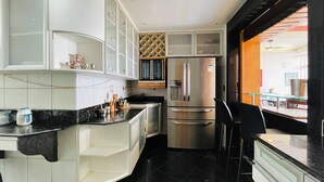 A modern kitchen with white cabinets, a stainless steel refrigerator, and a black countertop. - Frente Mar Encantador (Rio de Janeiro)
