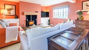Una sala de estar con chimenea, sofá y televisor.