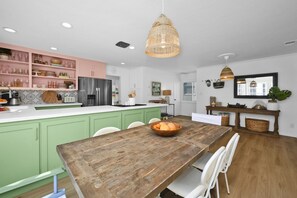 Eine moderne Küche mit grünen Schränken, einem Holztisch und einer Pendelleuchte.