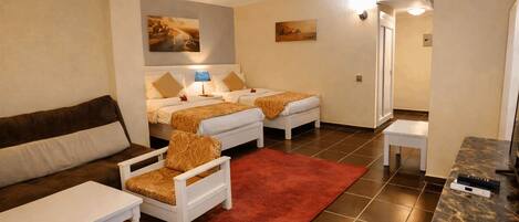 A hotel room with two beds, a sofa, a small table, a red rug, and a marble countertop.