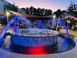 A circular pool with water jets and mosaic tiles, surrounded by lounge chairs and a covered area. - Viking Club Hotel (Sharm El Sheikh)