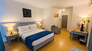 Une chambre d’hôtel comprenant un lit, des lampes de chevet, un bureau avec un ordinateur, une chaise et une petite table.