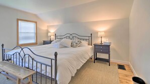 A bedroom with a metal bed frame, white bedding, two bedside tables with lamps, a wooden bench, and a window with blinds. - Walk to Beach! Sodus Point Escape w/ Private Yard (Sodus Point)