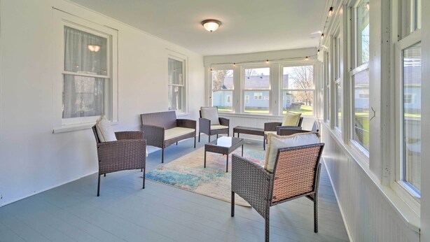 A covered porch with wicker furniture, large windows, and a ceiling light. - Walk to Beach! Sodus Point Escape w/ Private Yard (Sodus Point)