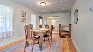 A dining area with a wooden table and chairs, a patterned rug, and a ceiling light fixture. - Walk to Beach! Sodus Point Escape w/ Private Yard (Sodus Point)