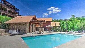 Un espace piscine avec des chaises longues, un bâtiment en pierre et une terrasse en bois.