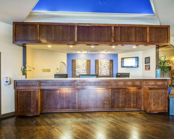 Una recepción con mostrador de madera, tragaluz y pared azul decorativa.
