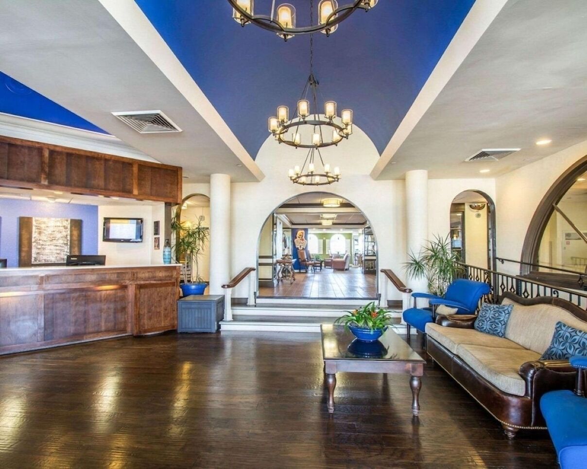 A spacious lobby with a reception desk, seating area, and a staircase leading to upper floors.