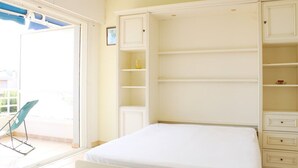 A bedroom with a bed, a sliding glass door to a balcony, and built-in storage cabinets. - Apartment for 6 in a standing residence with swimming pool (CAVALAIRE sur mer)