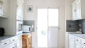 A kitchen with white cabinets, a microwave, and a wooden cabinet. - Apartment for 6 in a standing residence with swimming pool (CAVALAIRE sur mer)