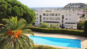 A hotel with a swimming pool, palm trees, and a view of the marina. - Apartment for 6 in a standing residence with swimming pool (CAVALAIRE sur mer)