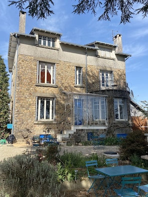 A stone building with multiple windows, a balcony, and outdoor seating.