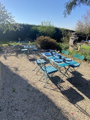 An outdoor seating area with tables and chairs, surrounded by gravel and greenery.