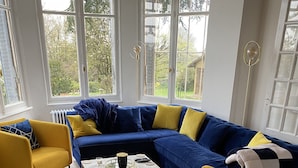 Ein modernes Wohnzimmer mit einem blauen Ecksofa, gelben Sesseln und einem Couchtisch.
