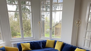 Ein modernes Wohnzimmer mit einem blauen Ecksofa, gelben Sessel und einem weißen Couchtisch.