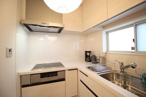 Een koelkast, een magnetron, een kookplaat, kookgerei, borden en bestek