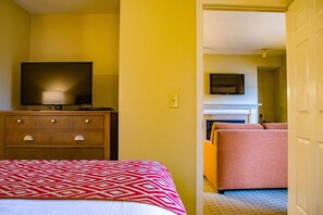 A hotel room with a bed, a dresser, a television, and a fireplace. - Pigeon Forge | Friends' Outdoor Escape | Hiking + Pool | 2BR Townhome (Pigeon Forge)