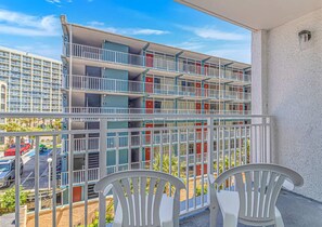 Un immeuble à plusieurs étages doté de balcons, d’un espace de stationnement et offrant une vue sur la rue.