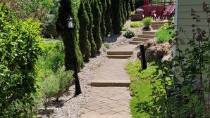 Un chemin pavé mène à un bâtiment où se trouvent une chaise rouge et un lampadaire.