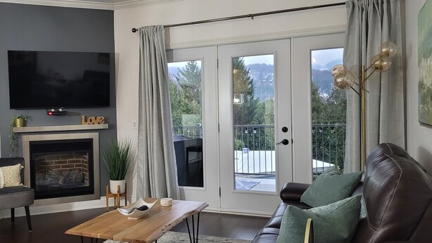 Un salon doté d’un téléviseur à écran plat, d’une cheminée et offrant une vue sur un balcon avec une balustrade.