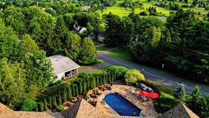 Un quartier résidentiel doté d’une piscine, entouré d’une végétation luxuriante et offrant une vue sur un paysage vallonné.