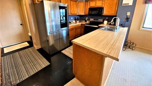 A modern kitchen with stainless steel appliances, wooden cabinets, and a large island. - BR260 Perfect for 2 couples! Close to Towns. (Davis)