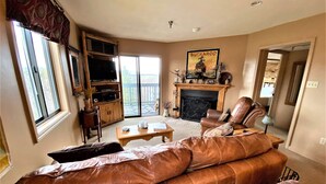 A living room with a leather sofa, a fireplace, a television, and a sliding glass door to the outside. - BR260 Perfect for 2 couples! Close to Towns. (Davis)