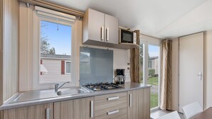 A modern kitchen with a gas stove, a microwave, and a sink. There is a dining table with chairs.