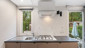 Eine kleine Küche mit Gaskochfeld, Spüle und Fenster zum Garten hinaus.