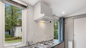 Eine moderne Küche mit großem Fenster, einer Spüle aus Edelstahl, einem Gasherd und weißen Schränken.