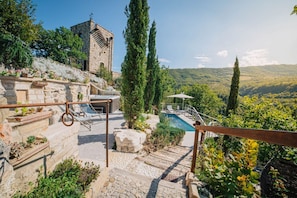 A stone staircase leading to a pool area with a view of a mountain and a tower.