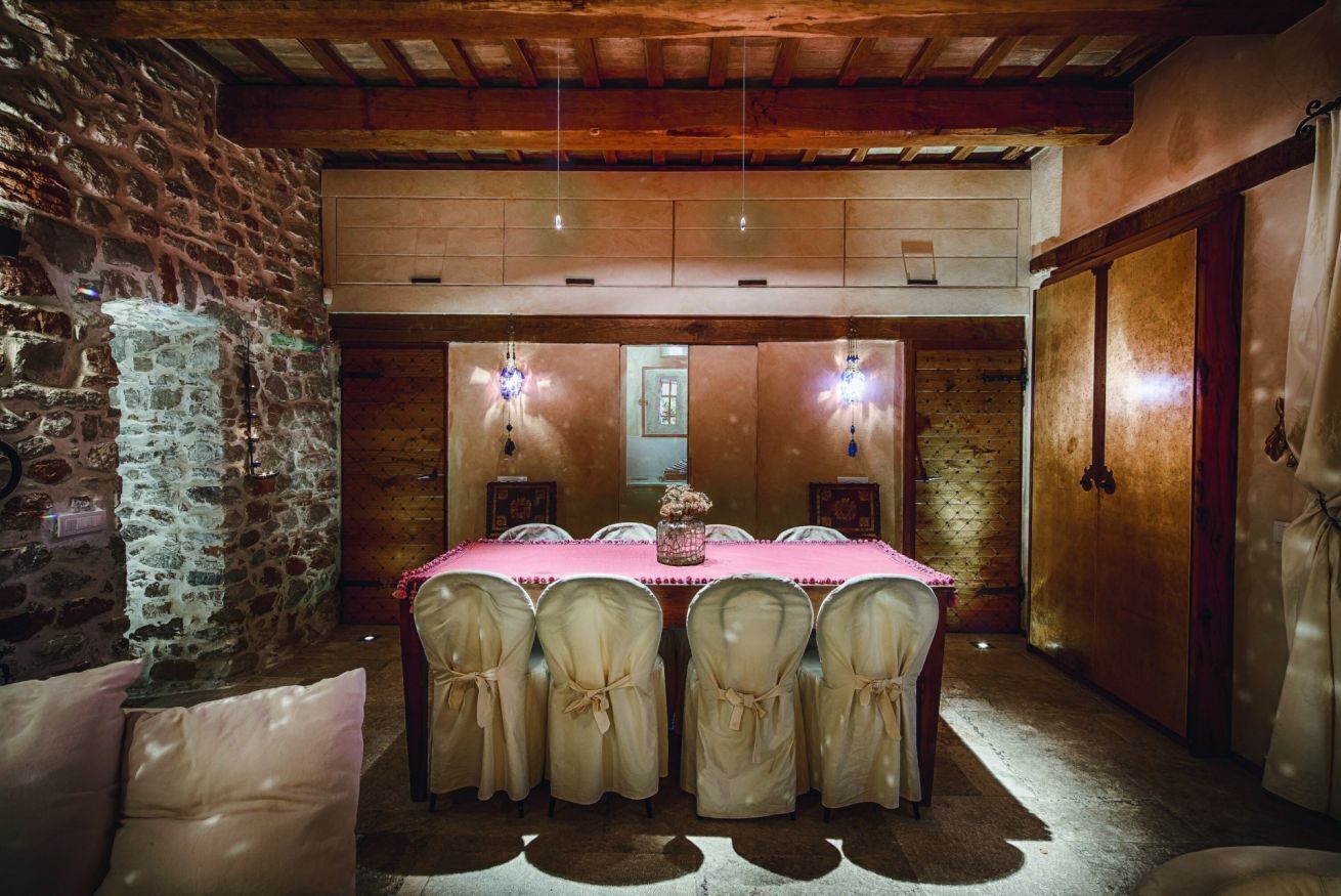 Un comedor con pared de piedra, techo de madera y una mesa con sillas.